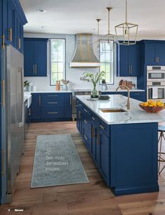 a large kitchen with blue cabinets and white counter tops, an island in the middle