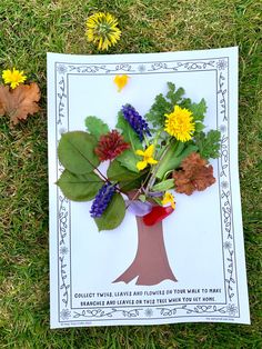 a paper tree with flowers and leaves on the ground next to some dandelions