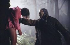 two people standing in the woods with their hands on each other's head and one person wearing a mask