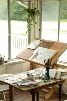 an artist's easel sitting on top of a wooden table next to a window