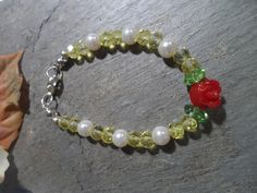 Handmade Beauty and the Beast bracelet Crystals mix, original design, Crystals beads in yellow Mixed with white glass pearls,  With a detail of a small red acrylic flower and two green glass beads similar to the green leaves of the flower, it has a silver tone lobster clasp. This yellow crystal bead bracelet mixed with glass beads is ideal for our princesses' daily wear or for their Beauty and the Beast theme birthday celebration. Green Plastic Bracelet Jewelry, Green Plastic Bracelet, Flower Shaped Plastic Jewelry As Gift, Flower-shaped Plastic Jewelry As Gift, Flower-shaped Plastic Jewelry Gift, Plastic Flower-shaped Jewelry For Gifts, Plastic Flower-shaped Jewelry As A Gift, Green Plastic Jewelry For Gifts, Green Plastic Round Bead Jewelry