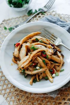 a white plate topped with pasta covered in sauce and garnished with green onions