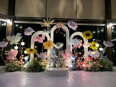 an elaborate display with flowers and lights in front of a window at the entrance to a building