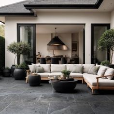 an outdoor living area with couches, tables and potted plants