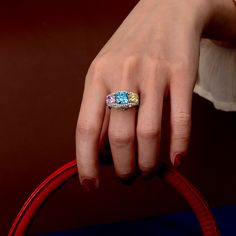 a woman's hand with a ring on it and two colored stones in the middle