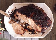 a large piece of meat sitting on top of a white plate next to a knife and fork