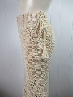 "Vintage 1970s hippy crochet skirt. Made of antique white cotton. Bohemian hippy style. Floor length with a drawstring waist. Crocheted on the bias so it is form fitting. Slight fish tail at bottom. No label. About a size medium. Actual measurements are: 32\"(adjusts bigger with drawstring) around the waist 38\" (stretches to 42\") around the hips 40\" overall length In very good condition." White Crochet Bottoms For Festival, Bohemian Crochet Bottoms For The Beach, Bohemian Cotton Skirt For The Beach, Bohemian Crochet Bottoms For Beach, Bohemian Cotton Skirt For Beach, Bohemian Crochet Lace Beach Bottoms, Bohemian Crochet Beach Bottoms, Cream Bohemian Bottoms For Vacation, Bohemian Cream Bottoms For Beach