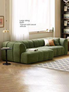 a green couch sitting on top of a hard wood floor next to a book shelf