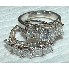 two wedding rings sitting on top of a white cloth covered tablecloth, with one diamond set in the middle