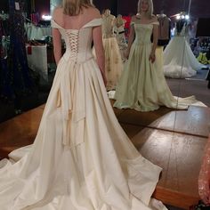 a woman in a wedding dress looking at herself in the mirror