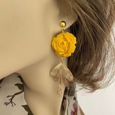 Introducing these exquisitely handcrafted Yellow Rose Clay Earrings, the perfect accessory for adding a touch of elegance to your outfit. Each pair is carefully made with attention to detail, ensuring a truly unique and beautiful piece. The brass accent adds a touch of sophistication, enhancing the overall design. With their delicate charm and undeniable beauty, these handmade earrings are sure to become a cherished addition to your jewelry collection. Made with 6mm gold plated stainless steel hypoallergenic posts.    Each earring is a one-of-a-kind handcrafted piece and is lightweight.  Care instructions:  Avoid using aerosol products, perfumes, jewelry cleaners or chemicals near the jewelry. Clean with a soft damp cloth or baby wipe.  Keep jewelry away from sharp objects to avoid scratch Elegant Polymer Clay Earrings With 3d Flowers, Gold Polymer Clay Jewelry With 3d Flowers, Gold Jewelry With 3d Flowers In Polymer Clay, Feminine Handmade Flower Jewelry For Gifts, Handmade Flower Earrings As Feminine Gift, Handmade Feminine Flower Earrings For Gifts, Feminine Handmade Flower Earrings For Gift, Elegant Gold Flower Earrings Polymer Clay, Elegant 3d Flowers Adjustable Earrings