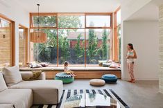 a woman standing in front of a window next to a child sitting on a bean bag chair