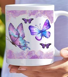 a woman holding a coffee mug with purple butterflies on it