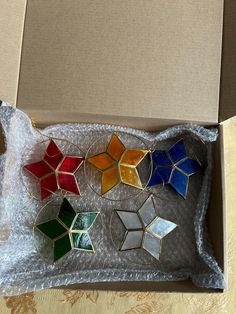 an open box with six different colored stained glass pieces in it on a table top