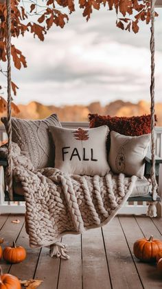 a porch swing with fall pillows on it