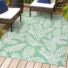 an outdoor area rug with blue and green leaves on it, sitting on a deck