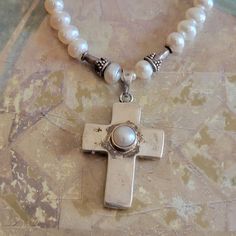 This is a vintage, sterling silver and pearl,  cross pendant on a pearl necklace with sterling beads and a sterling clasp. The pendant cannot come off of the necklace. This has tested positive for sterling. All sales are final.  The necklace measures a bit over 16  inches. The cross measures 39 mm x 22 mm across.   If you have a wish list or are looking for something specific, please ask. I may have exactly what you are looking for.  As always please convo me with any questions or concerns regarding this item or with any international shipping questions. Unfortunately I do not accept returns or grant refunds. All shipping fees include handling fees. If you would like to combine shipping costs for more than one item, I would be happy to do so if you convo me before purchase.  Purchasing my Silver Cross Pearl Pendant Necklace, Silver Cross Necklace With Pearl Drop, Silver Pearl Cross Pendant Necklace, Silver Pearl Necklace With Cross Pendant, Silver Cross Pendant Pearl Necklace As Gift, Silver Pearl Necklace With Cross Pendant For Gift, Spiritual Cross-shaped Pearl Necklace As Gift, Spiritual Cross Pearl Necklace Gift, Spiritual Cross Pearl Necklace As Gift