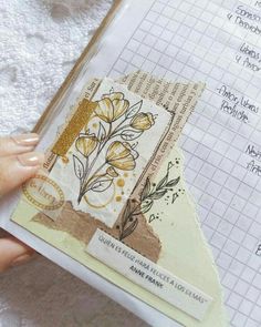 a person holding a piece of paper with flowers on it in front of a notebook