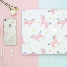 a pink and blue desk with flowers, headphones, an iphone and a laptop on it