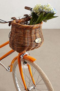 a basket on the back of a bicycle with flowers in it