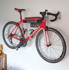 a red bike mounted to the side of a wall next to a bookshelf