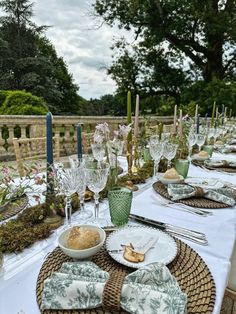 the table is set with dishes and place settings for an outdoor dinner or party event