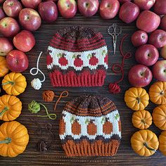 an assortment of apples, oranges and other fruit on a table with knitted hats