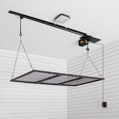 two suspended lights in a room with white walls and black ceiling tiles on the wall