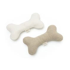 two bone shaped pillows are shown on a white background, one is made out of wool and the other has a dog bone