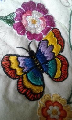 embroidered butterflies and flowers on a white fabric material with multi - colored threadwork, closeup