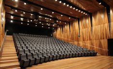 an empty auditorium with wooden walls and black seats