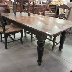 a large wooden table surrounded by chairs in a room with other furniture on the floor