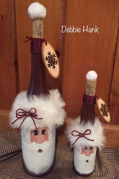 two wine bottles decorated like santa claus and snowmen with wooden spoons in them