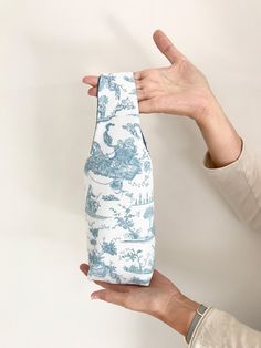 a person holding up a blue and white vase