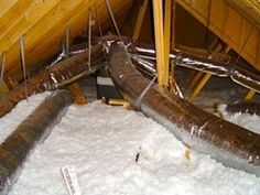 an attic with exposed pipes and snow on the floor