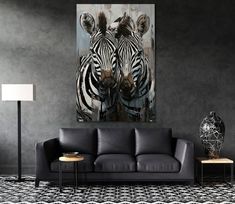 two zebras standing next to each other on a wall in a room with black walls