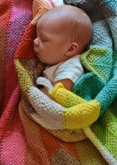 a baby wrapped in a multicolored blanket