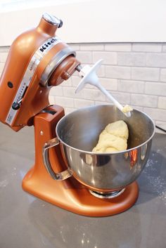 an orange mixer with some dough in it