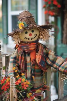 a scarecrow sitting on top of a wooden fence