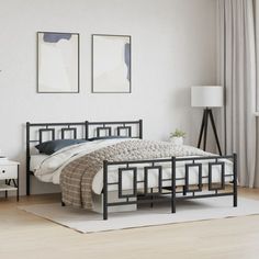 a bedroom with white walls and wood flooring, two pictures on the wall above the bed