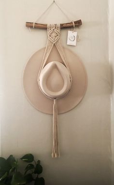 a white hat hanging on the wall with a wooden stick and string attached to it