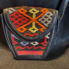 This Handmade Bag Is Beautifully Crafted With Blank Leather And 100% Dyed Wool Kilim From Turkey. This Bag Was Never Used, Safely Stored With The Original Tags And Information. It Has A Magnetic Closure, Adjustable 50 Inch Strap With Brass Hardware, Original Had Tag, And Information Tag With Price. The Kilim Has A Black Background With A Red, Brown, Orange, Gray, And Green One Of A Kind Design. You Will Not See This Bag Coming And Going. Unique And Stunning! Retro Black Crossbody Shoulder Bag, Vintage Black Satchel With Mobile Phone Bag, Traditional Black Travel Bag, Vintage Black Bag With Adjustable Strap, Traditional Black Rectangular Shoulder Bag, Black Retro Shoulder Bag With Removable Pouch, Retro Black Shoulder Bag With Removable Pouch, Traditional Black Tote Shoulder Bag, Vintage Black Pouch Shoulder Bag