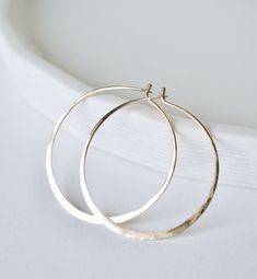 Gold hoop earrings, a simple classic. Hammered hoops out of 18 gauge, 14K gold filled wire - a staple for any wardrobe. Shiny and organic, each one a little unique from the other since they've been formed and hammered by hand. Three sizes available: Small hoops -  approximately 1 1/4" in diameter Medium hoops - approximately 1 5/8" in diameter Large hoops - approximately 2" in diameter Minimalist Hand-forged 14k Gold Hoop Earrings, Small Hammered Gold-plated Hoop Earrings, Small Hoop Earrings In Gold-tone Brass, Hammered 14k Gold-filled Hoop Earrings, Earrings Gold Hoops, Gold-tone Polished Metal Hoop Earrings, Hoop Earrings Gold, Gold Hoops, Gold Hoop