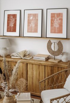 three framed pictures hang on the wall above a wooden cabinet in a room with wicker furniture