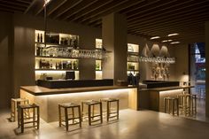 an empty bar with stools and bottles on the shelves in front of it at night