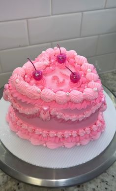 a pink cake with cherries on it sitting on a counter