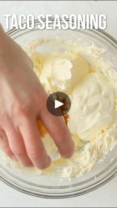 someone is mixing cream in a bowl with their hand on top of the whipped cream