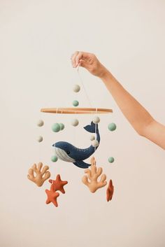 a hand is holding an animal mobile with sea creatures hanging from it's strings