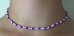 a purple and white beaded necklace on a woman's neck, with an earring