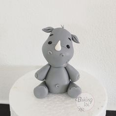 a small gray toy sitting on top of a white cake